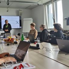 Seven attendees at IndieWebCamp inside a large conference room at CGI Düsseldorf