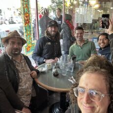 Selfie taken with four other participants in a mirror, all sitting around a round table waiting for their brunch orders.