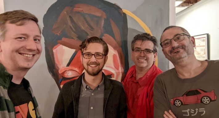 From left to right: gRegor Morrill, Jordan Yonts, Joe Crawford, and Simon Prickett standing in front of a painting of David Bowie