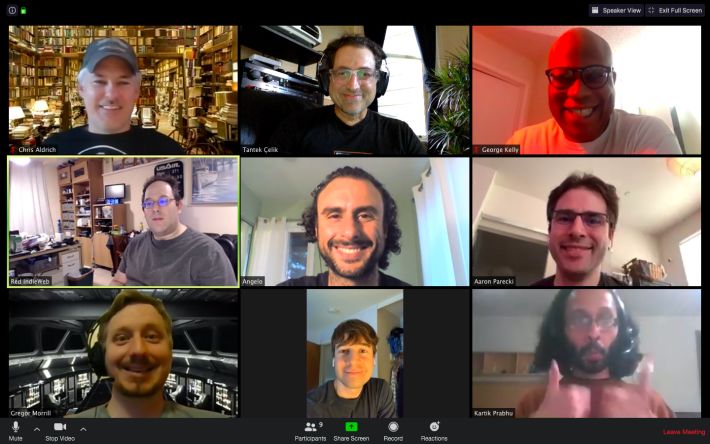 Nine video participants in a 3x3 grid with various backgrounds, some at home, some with graphics.